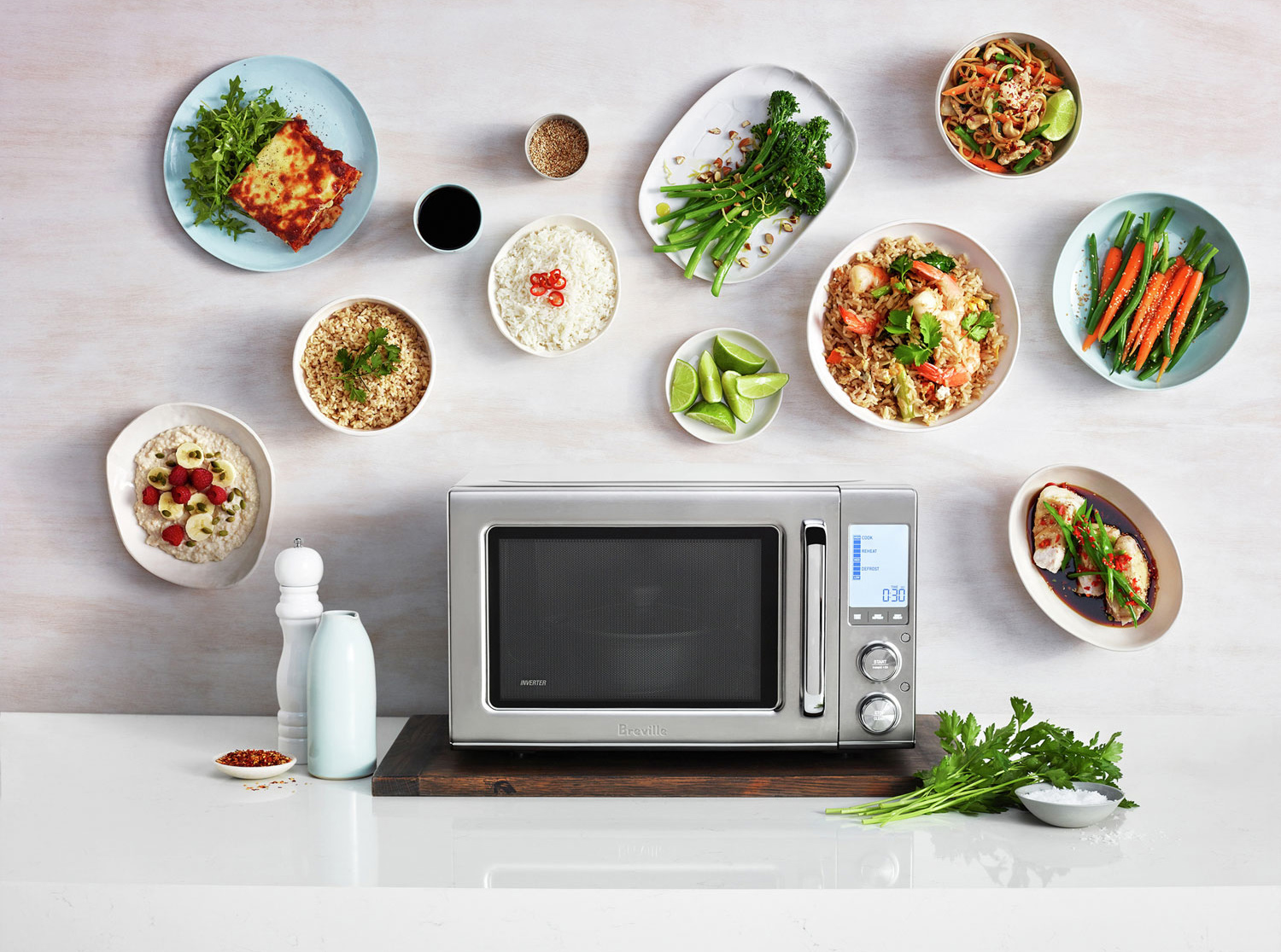 A microwave surrounded by plates of food