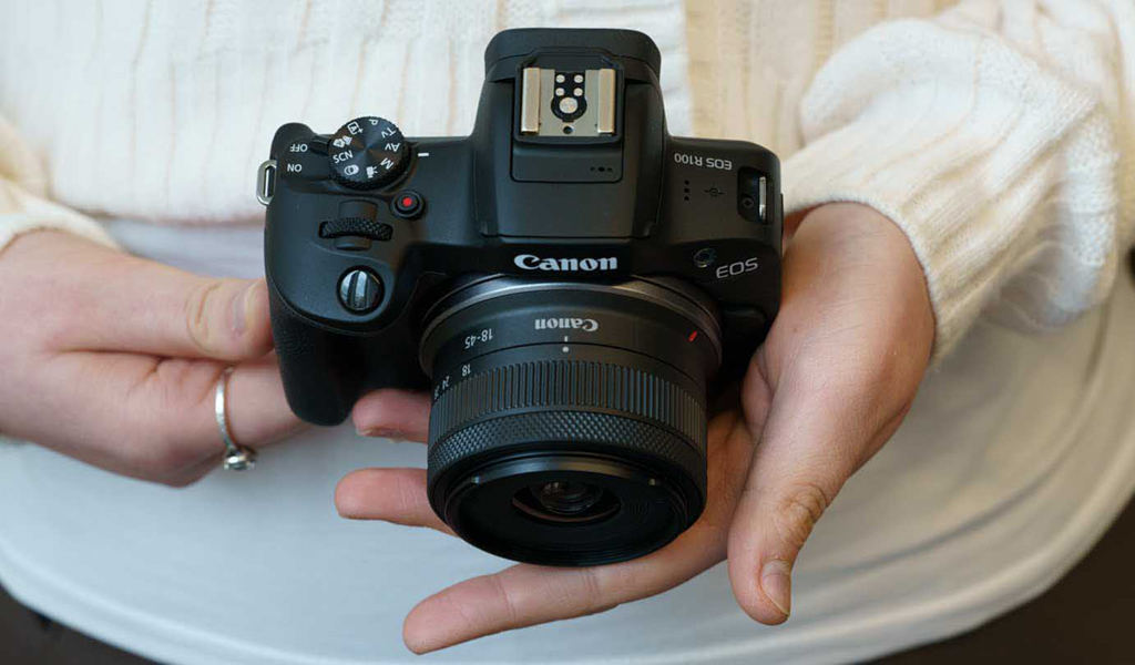 Someone holding the Canon EOS R100.