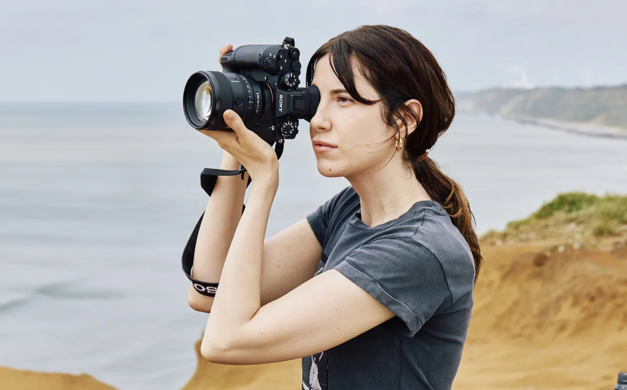 Femme prenant des photos avec un Sony Alpha 1 II à l'extérieur.