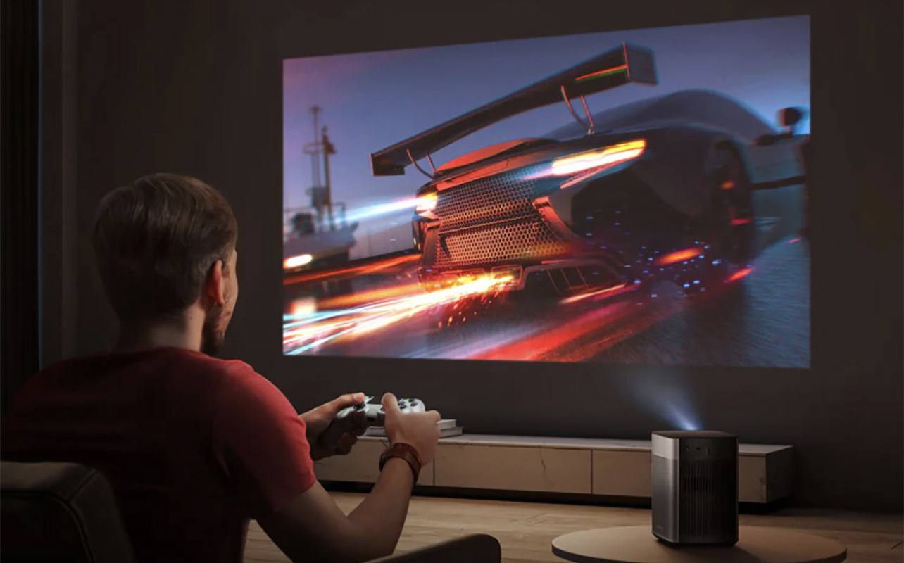 A man playing a video game on a large screen using an Xgimi Halo Plus projector